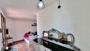 A bedroom with a bed, a dresser, a mirror, and a hanging light fixture. - Villetta Volterraio in Rio Elba (Rio dell'Elba)