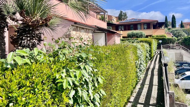 A residential area with houses, a paved pathway, and a parked car. - Villetta Volterraio in Rio Elba (Rio dell'Elba)
