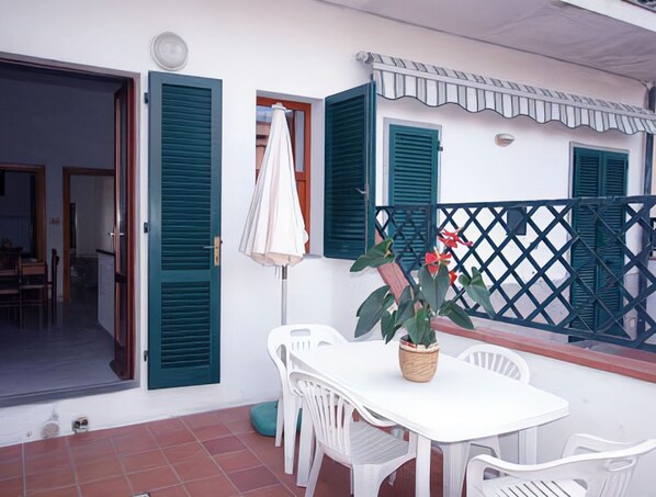 A patio with a white table and chairs, a potted plant, and a lattice fence.