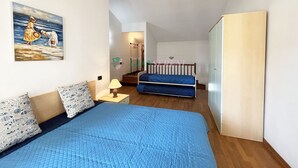 A bedroom with a bed, a nightstand, a lamp, a wardrobe, and a painting on the wall. - TWO-ROOM APARTMENT SLEEPS 5 IN THE CENTRAL AREA (San Vincenzo)