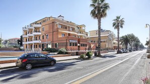 A street with a multi-story building featuring balconies and a sign that reads "Cassa di Risparmio di Volterra". - TWO-ROOM APARTMENT SLEEPS 5 IN THE CENTRAL AREA (San Vincenzo)