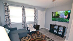 A living room with a sofa, a chair, a TV, and a patterned rug.