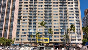 A high-rise hotel with multiple balconies, a marina with boats, and palm trees in front. - Ocean and Marina View Suite, Spacious, Quiet and Peaceful with Amazing Sunsets (Honolulu)