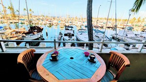 A wooden table with chairs, a cup of coffee, and a half-eaten dragon fruit on a balcony overlooking a marina with numerous boats. - Ocean and Marina View Suite, Spacious, Quiet and Peaceful with Amazing Sunsets (Honolulu)