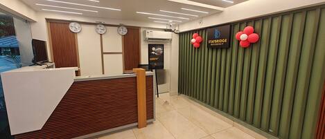 A reception area with a modern design, featuring a reception desk, clocks, and a wall-mounted sign for Staybridge Residency.