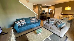 A modern living room with two sofas, a coffee table, and a staircase leading to an upper level. - Nice 4bd townhouse near Disney (Kissimmee)