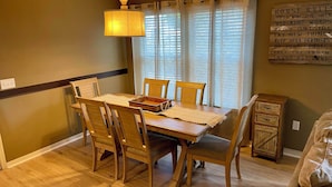 A dining area with a wooden table, four chairs, a woven placemat, and a lamp. - Nice 4bd townhouse near Disney (Kissimmee)