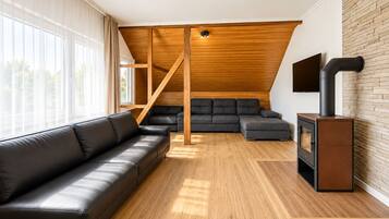 Ein modernes Wohnzimmer mit Holzbalkendecke, Kamin und großem Fenster.