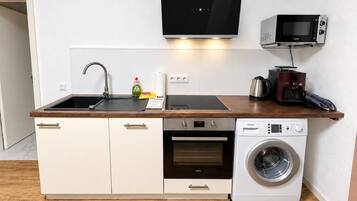 A compact kitchen with a sink, microwave, oven, and washing machine.