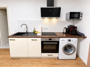 A compact kitchen with a sink, stove, microwave, and a built-in washing machine. - Our resin dream (Blankenburg (Harz))