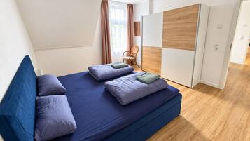 Quarto moderno com uma cama grande, um guarda-roupa de madeira e uma cadeira.