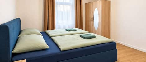 Une chambre avec un lit, une armoire et une fenêtre avec des rideaux.