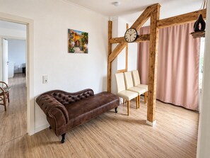 A room with a brown leather sofa, a wooden chair, a clock, and a painting on the wall. - Our Resin Dream (Blankenburg (Harz))