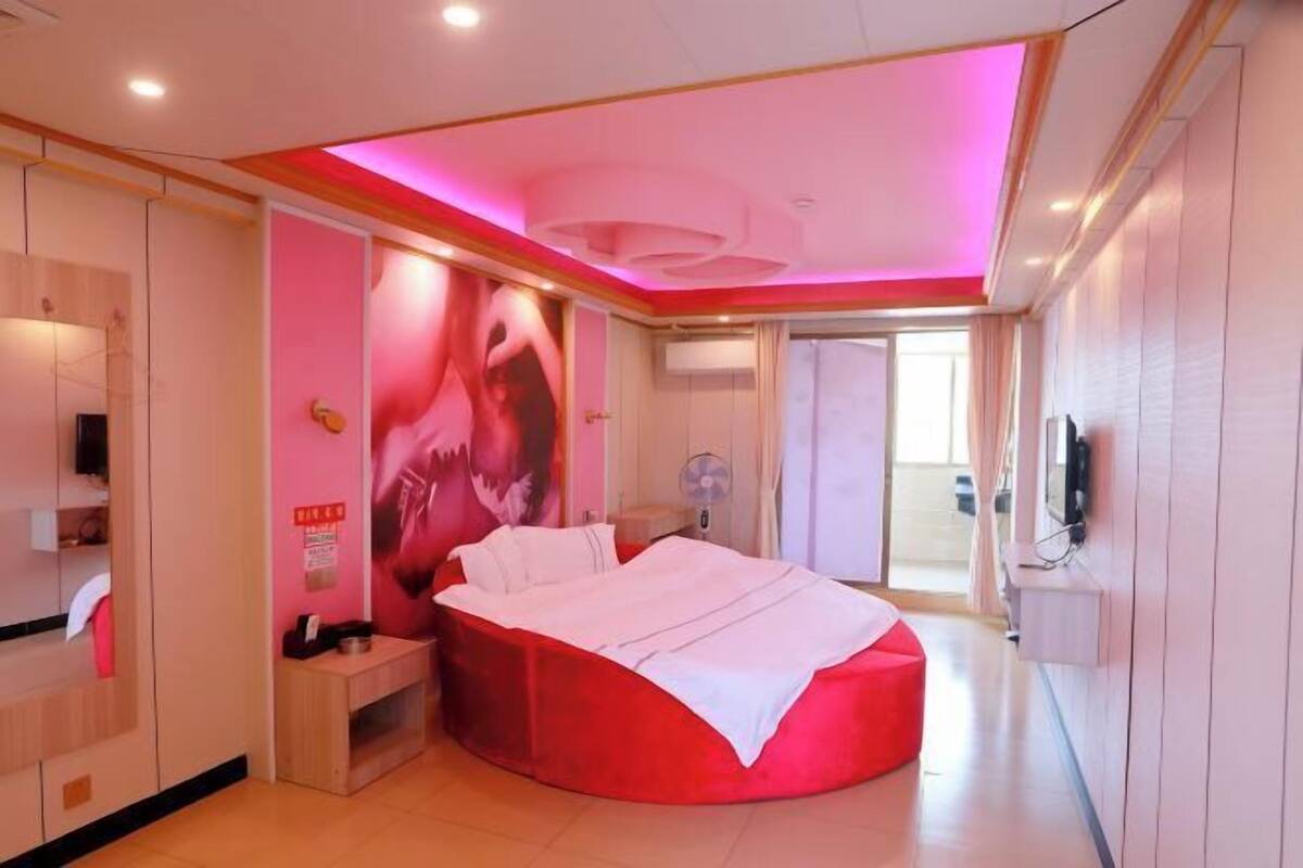 A modern bedroom with a curved bed, a vanity, and a large mirror.