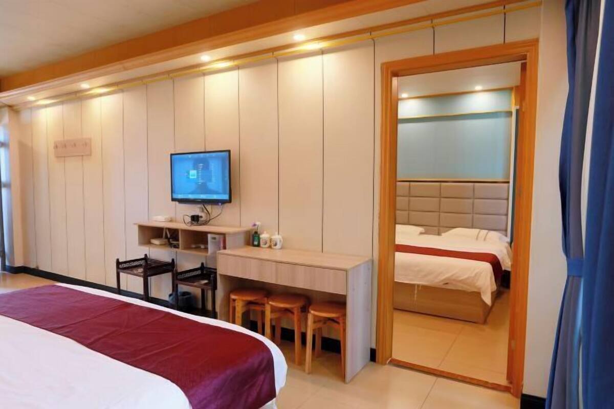 A hotel room with a bed, desk, chair, television, and a separate sleeping area.