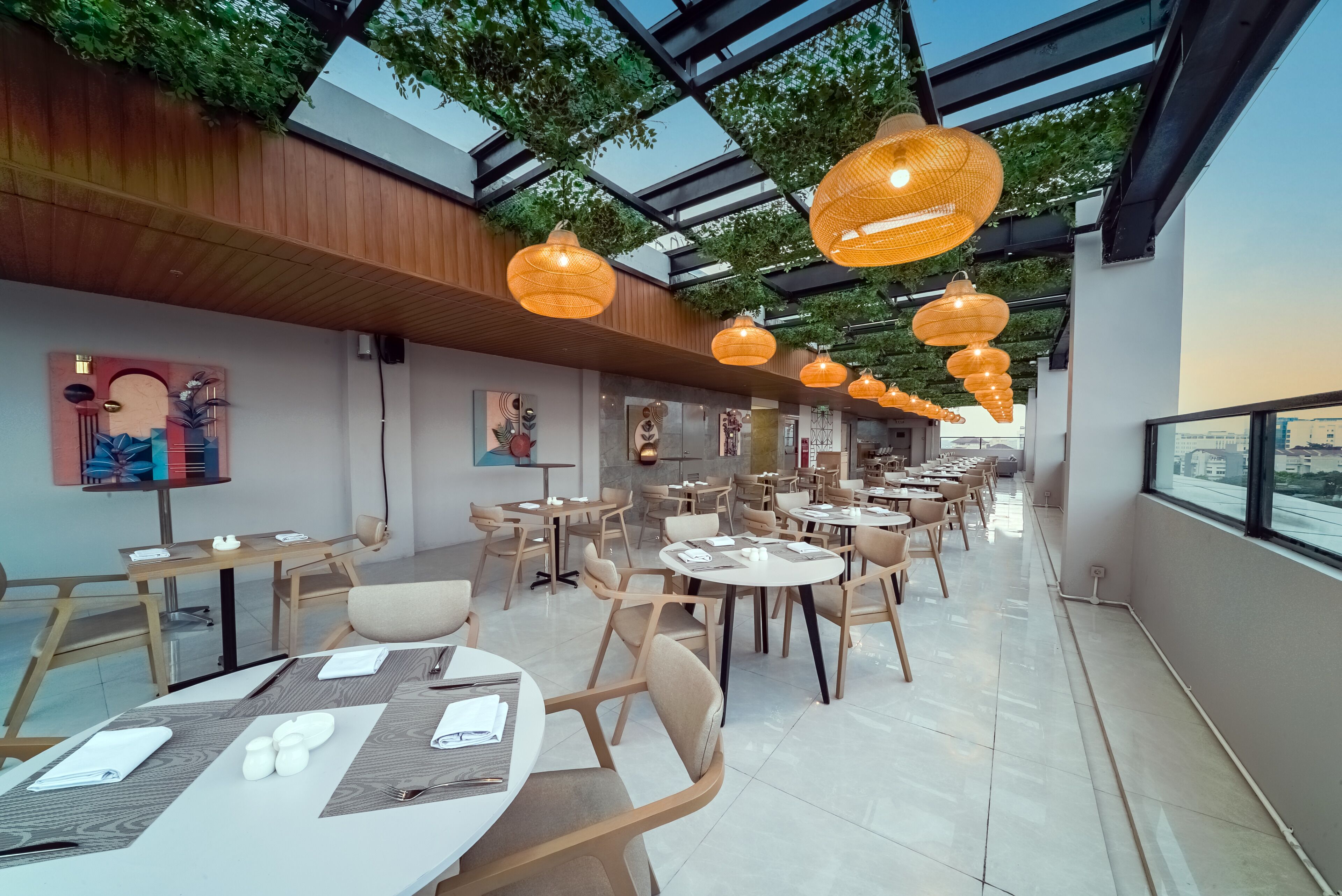 Un restaurant moderne avec des tables rondes, des chaises en bois et des lanternes suspendues.