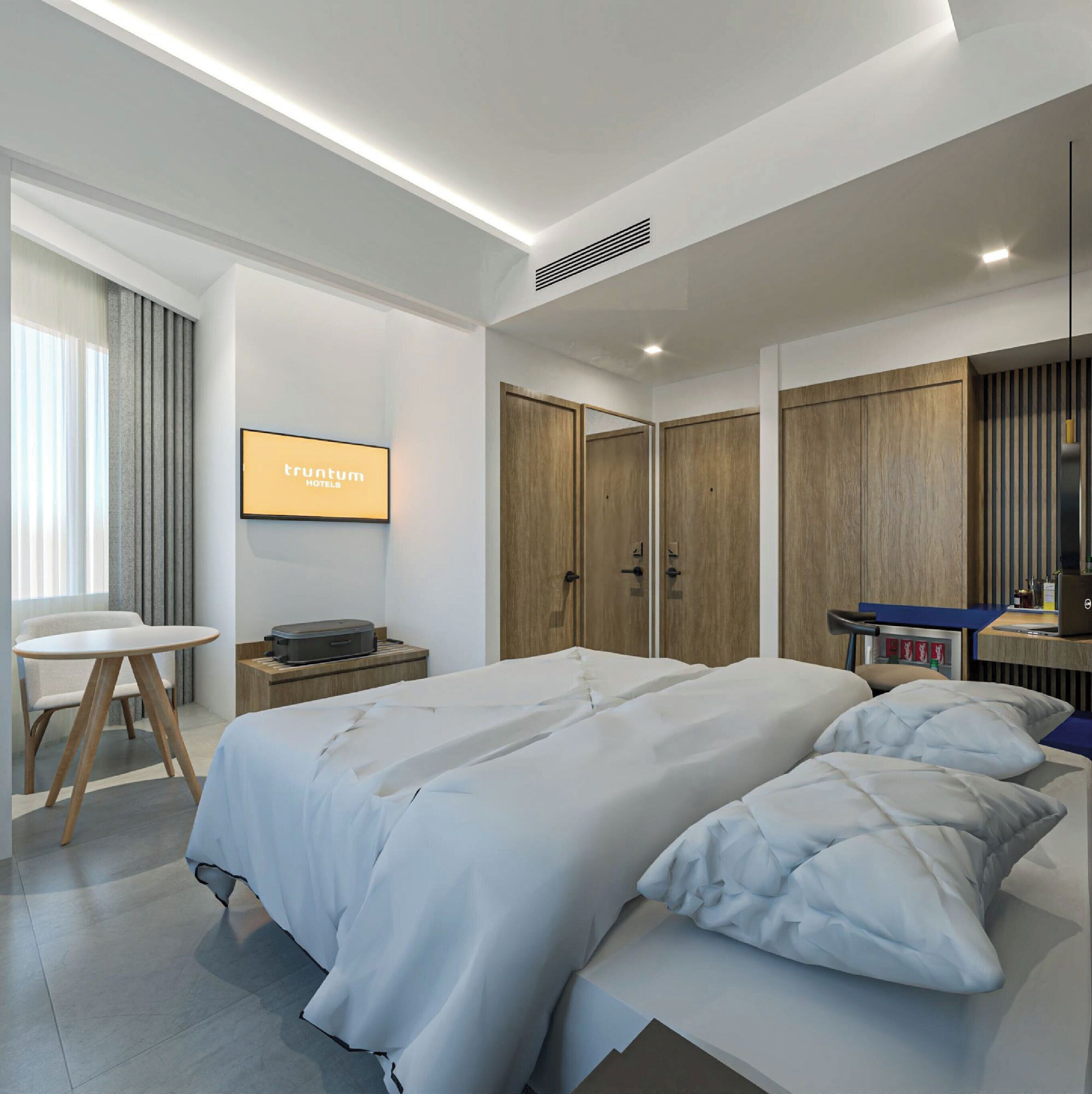 A modern hotel room with a large bed, a desk, and a wardrobe.