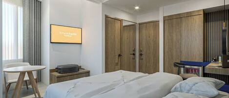 A modern hotel room with a large bed, a desk, and a wardrobe.