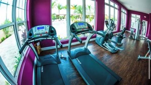A gym with treadmills and exercise equipment, large windows, and a view of greenery outside. - Cozy 3bd home 15 min from Disney (Kissimmee)