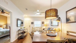 A modern living room with a dining area, a ceiling fan, and a large woven light fixture. - Cozy 3bd home 15 min from Disney (Kissimmee)