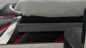 A bedroom with a bed, a door, a painting, and a rug. - Carrington Cozy Suite, Calgary (Calgary)