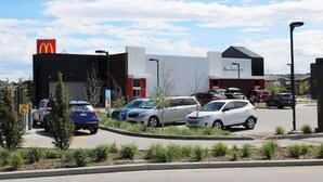 A McDonald's restaurant with a parking lot and a building with a sign that reads "ACOTS." - Carrington Cozy Suite, Calgary (Calgary)