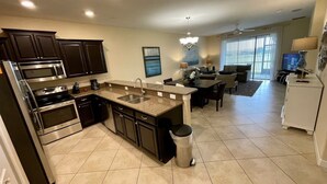 A modern kitchen with dark cabinetry, a granite countertop, and stainless steel appliances. - Resort Champions Gate 2 Bd/2Bh - Golf view (Davenport)