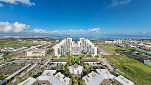 A large hotel with multiple buildings, a parking lot, and a view of the ocean.