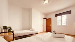 Habitación de hotel con dos camas, una planta en maceta y una ventana con persianas.