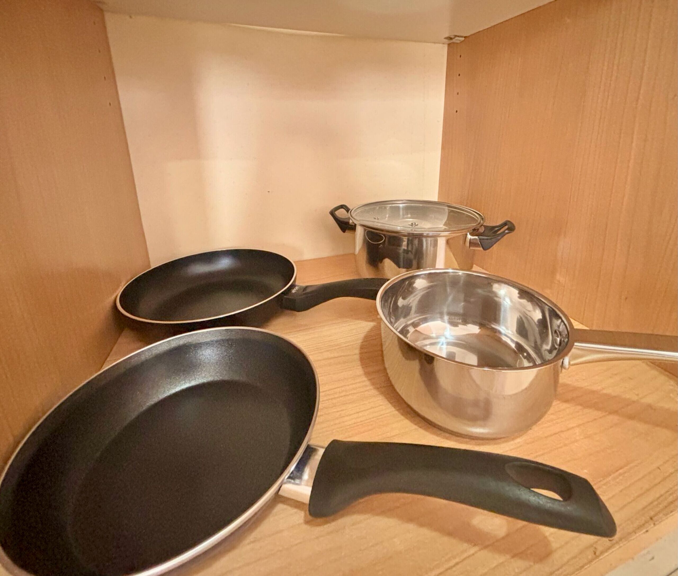 Een keuken met drie kookgerei items: twee koekenpannen en één pan.