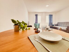 Una mesa de comedor con un plato, un tenedor y una servilleta, una planta en maceta y un sofá en una sala de estar.