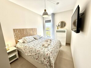 A bedroom with a bed, bedside table, dresser, and a TV mounted on the wall. - El rincon de candor by staycare (Rota)