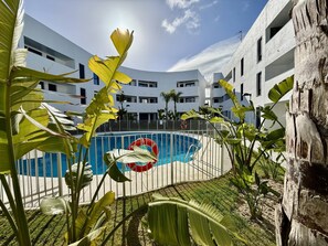 A modern building with a swimming pool surrounded by tropical plants. - El rincon de candor by staycare (Rota)