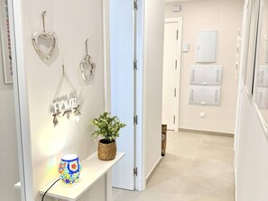 A hallway with a white door, a wall-mounted sign reading 'WELCOME', and a potted plant on a shelf. - El rincon de candor by staycare (Rota)