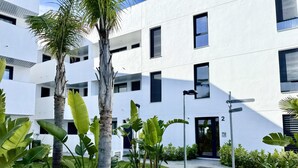 Un bâtiment moderne à la façade blanche, doté de nombreuses fenêtres et d’un petit hall d’entrée.