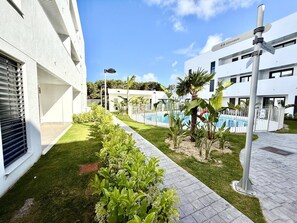 A modern building with a swimming pool, surrounded by well-maintained greenery and a clear sky. - El rincon de candor by staycare (Rota)