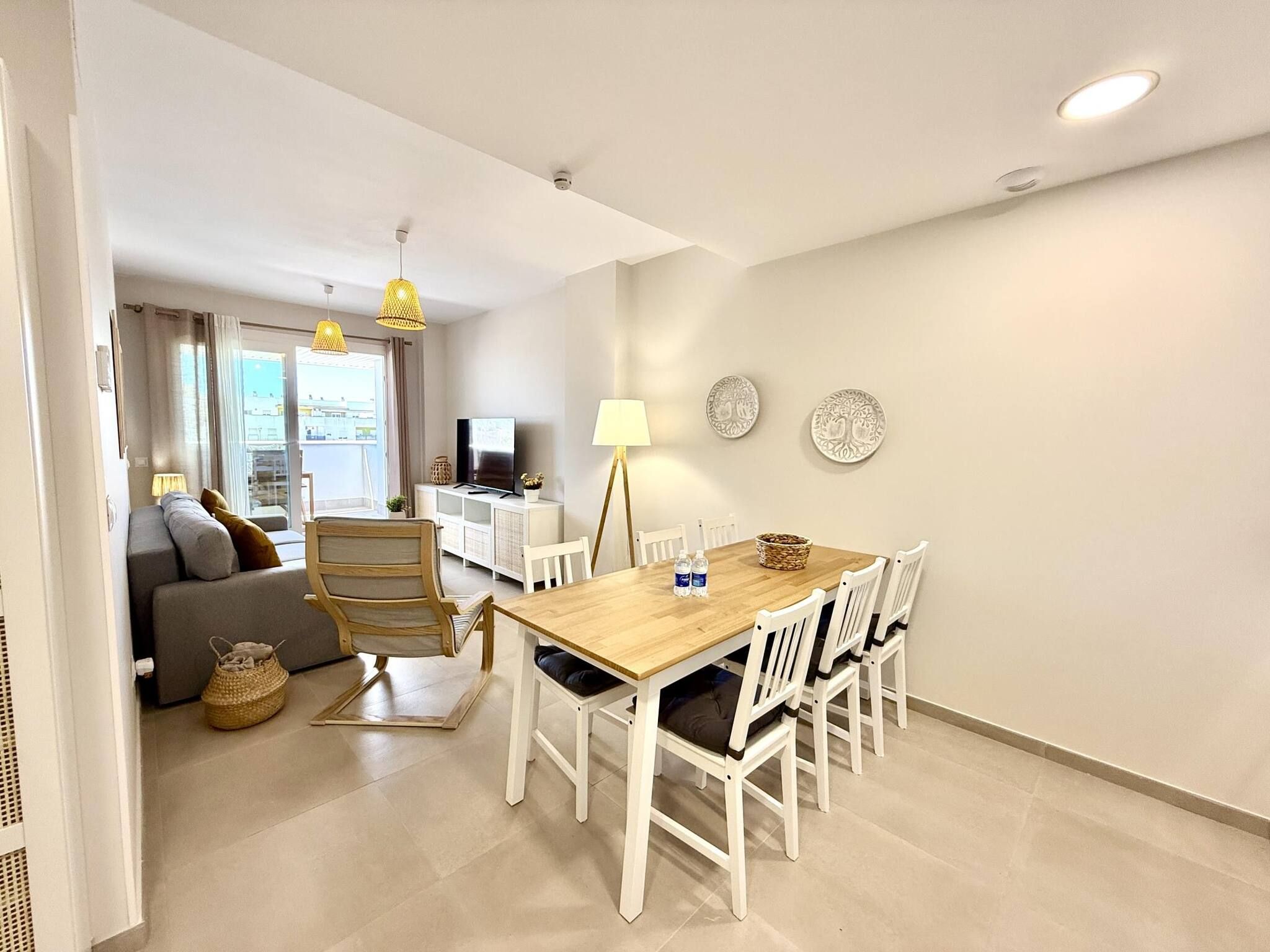 Ein modernes Wohnzimmer mit einer Couch, einem Esstisch mit Stühlen, einem Fernseher und Wanddekoration.