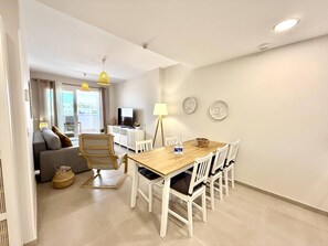 A modern living room with a sofa, a dining table with chairs, a TV, and decorative wall art. - El rincon de candor by staycare (Rota)