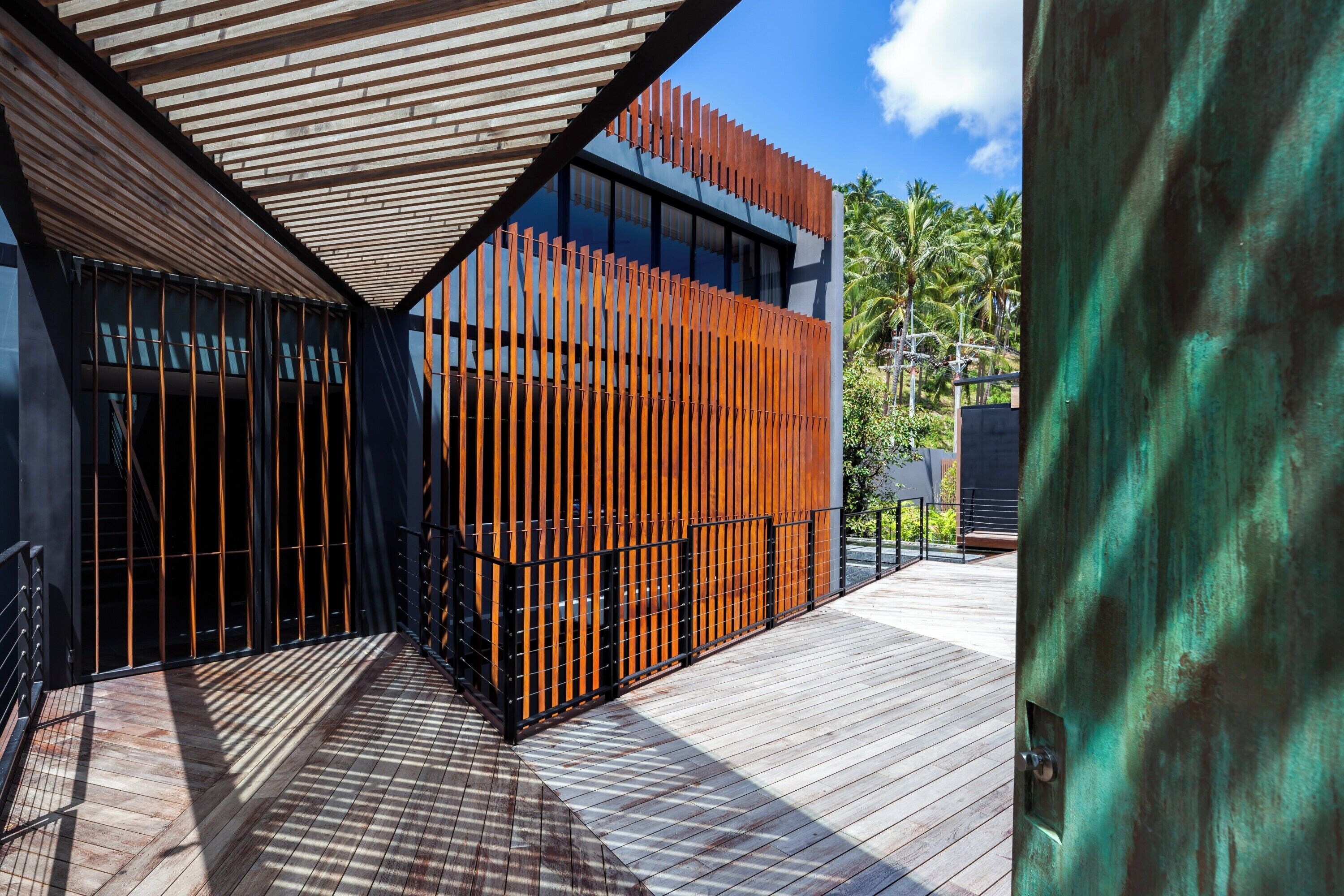 A modern building with a wooden deck, metal railings, and a glass facade.