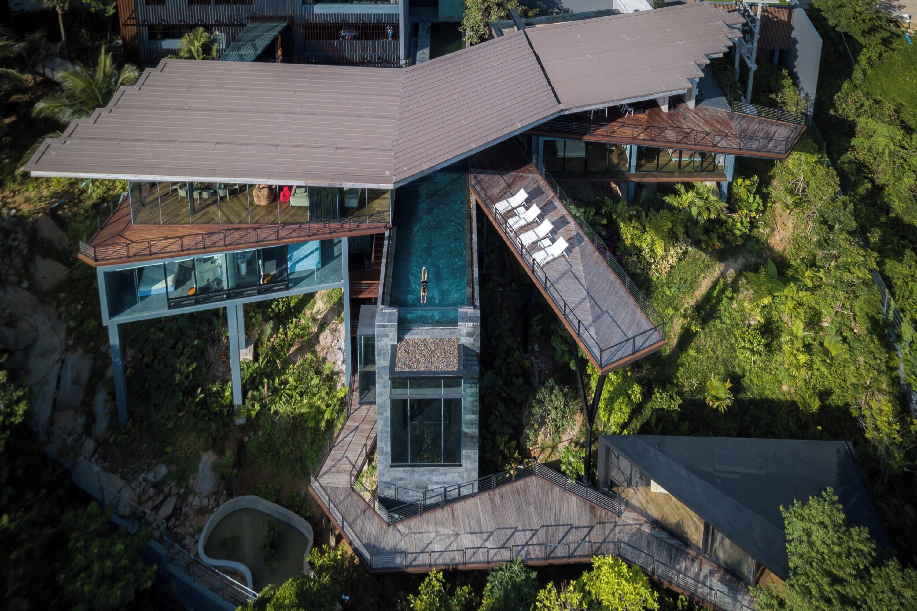 A modern house with a large swimming pool, multiple decks, and a unique architectural design.