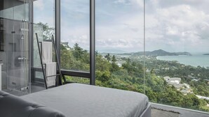 A bedroom with a large window overlooking a coastal landscape. - Kelapa House (Koh Samui)