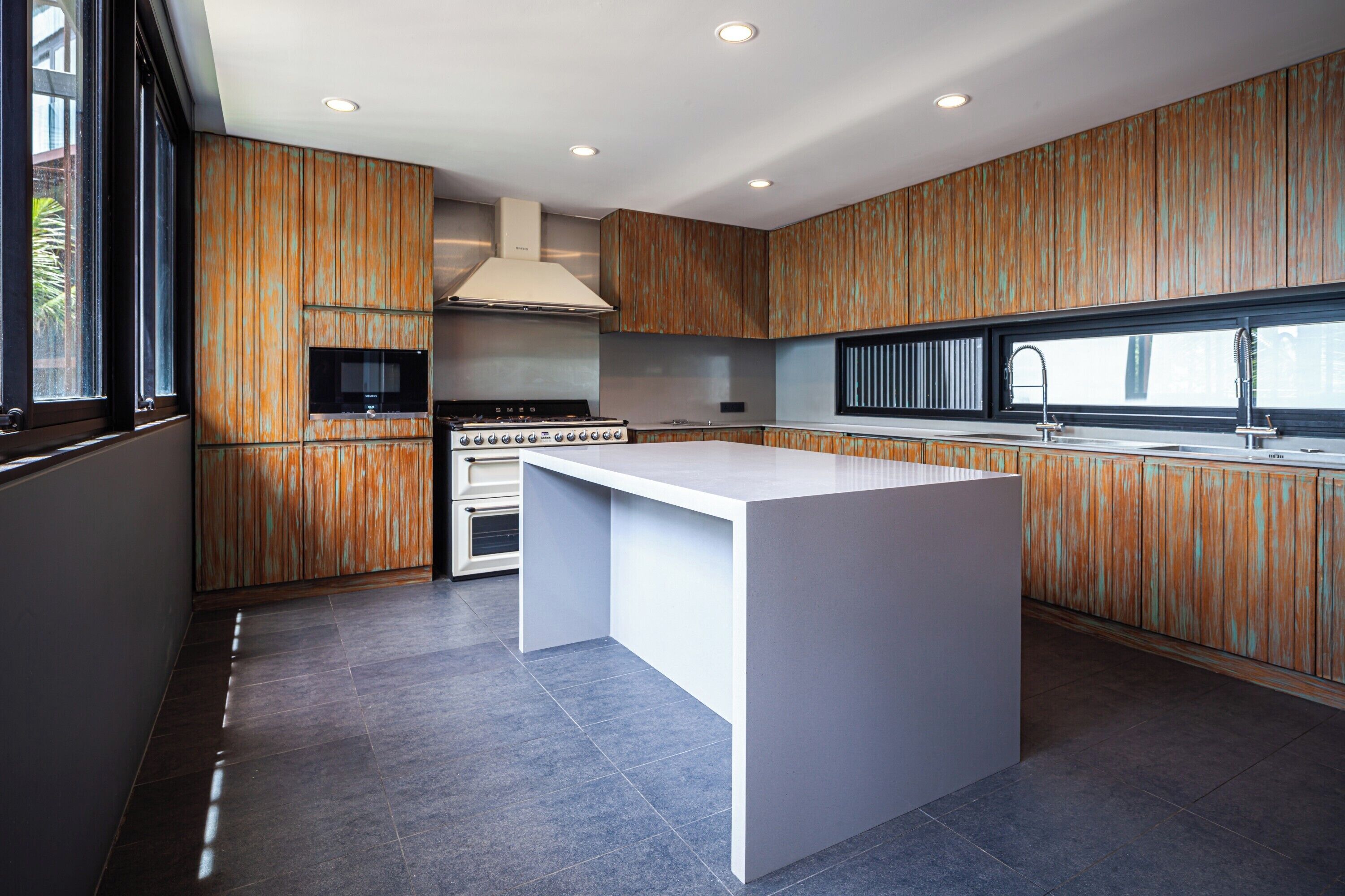 Een moderne keuken met een centraal eiland, inbouwapparatuur en houten lambrisering.