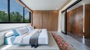 A modern bedroom with a large bed, a view of greenery outside, and a sliding door leading to a balcony. - Modern 2BR Villa Rooftop & Pool (Kuta Utara)