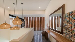A modern bathroom with a large mirror, a wooden vanity, and three woven pendant lights. - Modern 2BR Villa Rooftop & Pool (Kuta Utara)