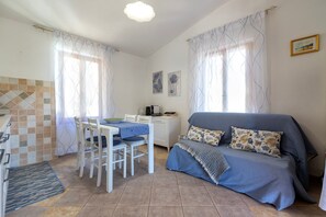 A compact living space with a dining area, a sofa with patterned cushions, and a kitchenette.
