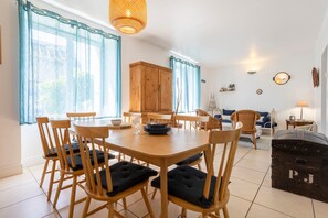 Un comedor con mesa y sillas de madera, un armario y una zona de estar acogedora con cojines.