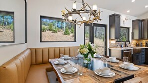 Een moderne eethoek met een houten tafel voor zes personen, een lederen bank en een kroonluchter versierd met geweiën.
