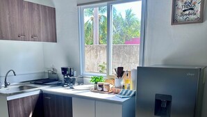 A modern kitchen with a built-in dishwasher, a window with a view of greenery, and a refrigerator.