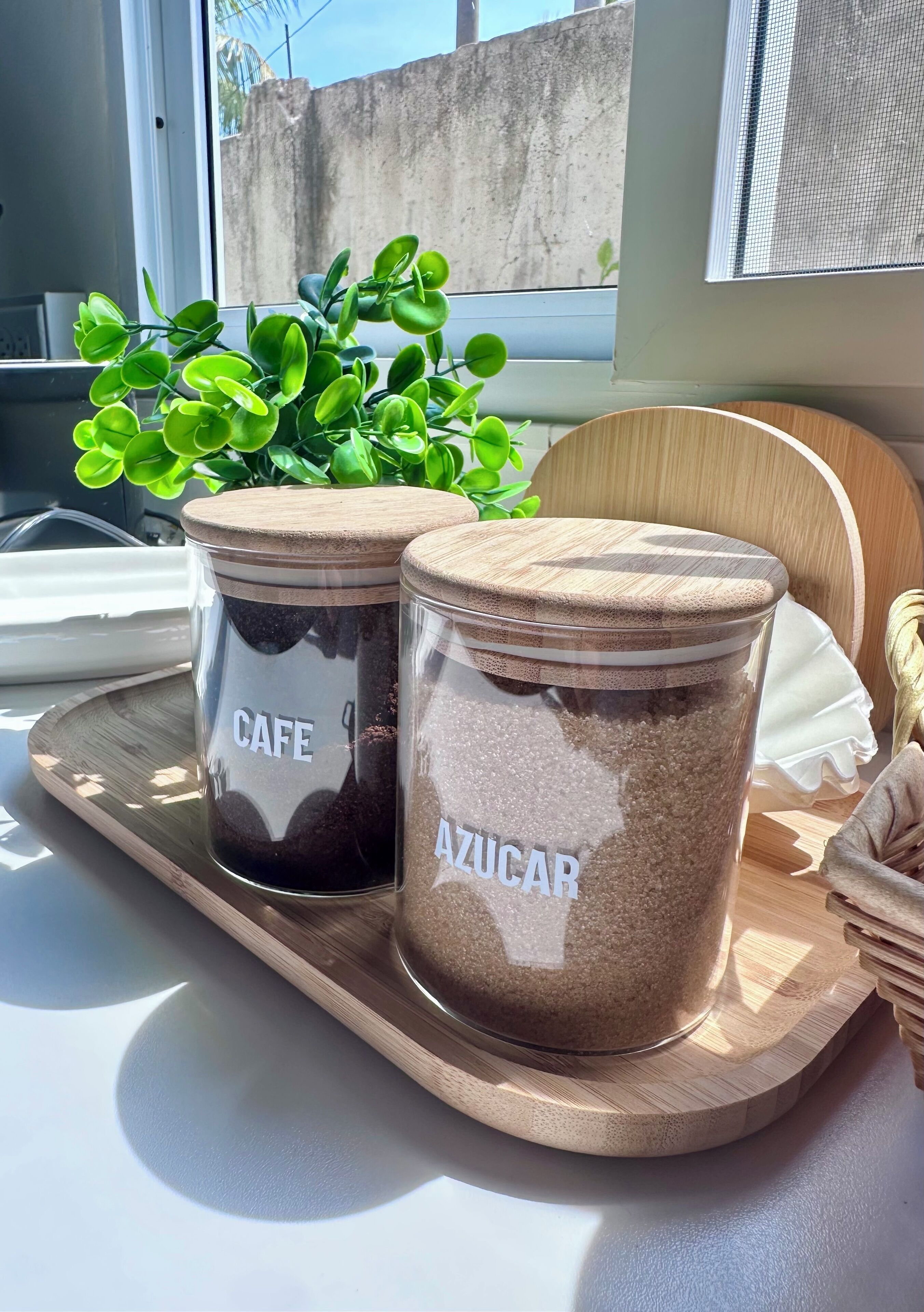 Two glass jars with wooden lids labeled "CAFE" and "AZUCAR" on a wooden tray.