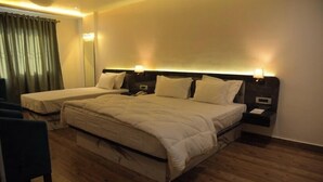 A hotel room with a large bed, two bedside tables, a chair, and a mirror. - Hotel Golden Leaf (Ranchi)